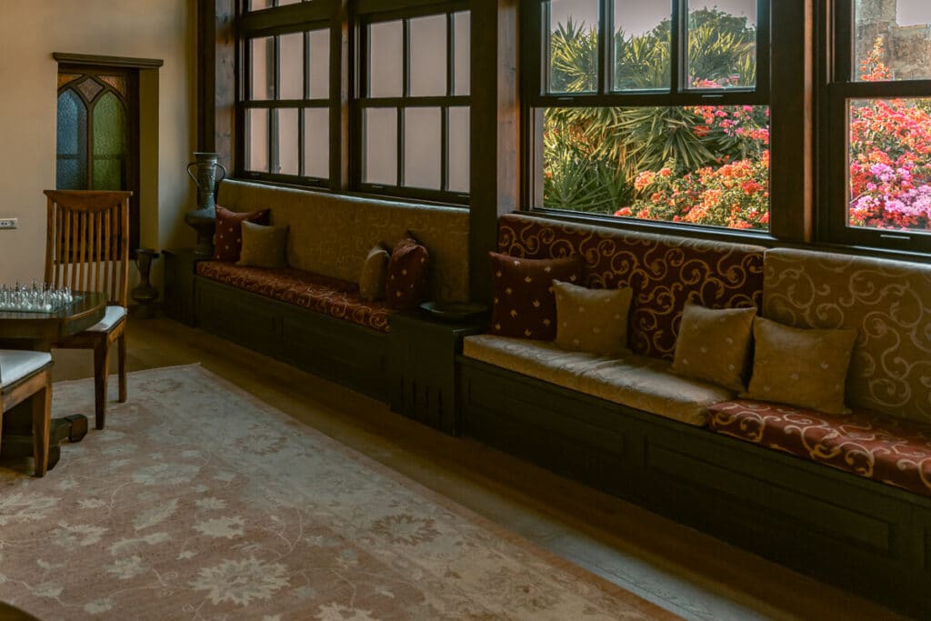 Sitting area inside Spirit of the Knights Boutique Hotel in Rhodes Old Town, with cushioned window benches, wooden details, and garden views.