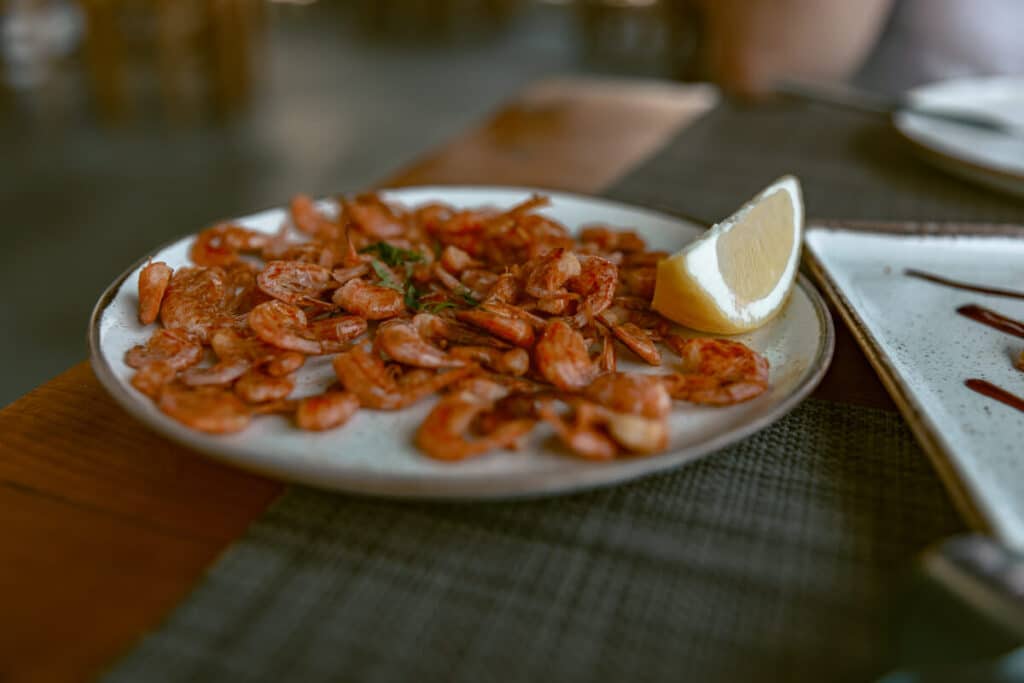 Plate of Symi shrimp served with lemon at a restaurant, one of the seafood dishes to try near Rhodes.