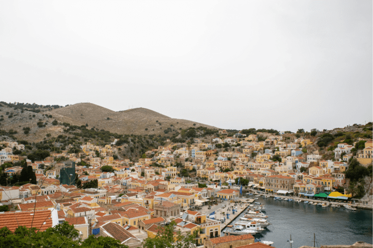 Colorful neoclassical houses surrounding the harbor on Symi, a scenic arrival on a day trip to Symi from Rhodes.