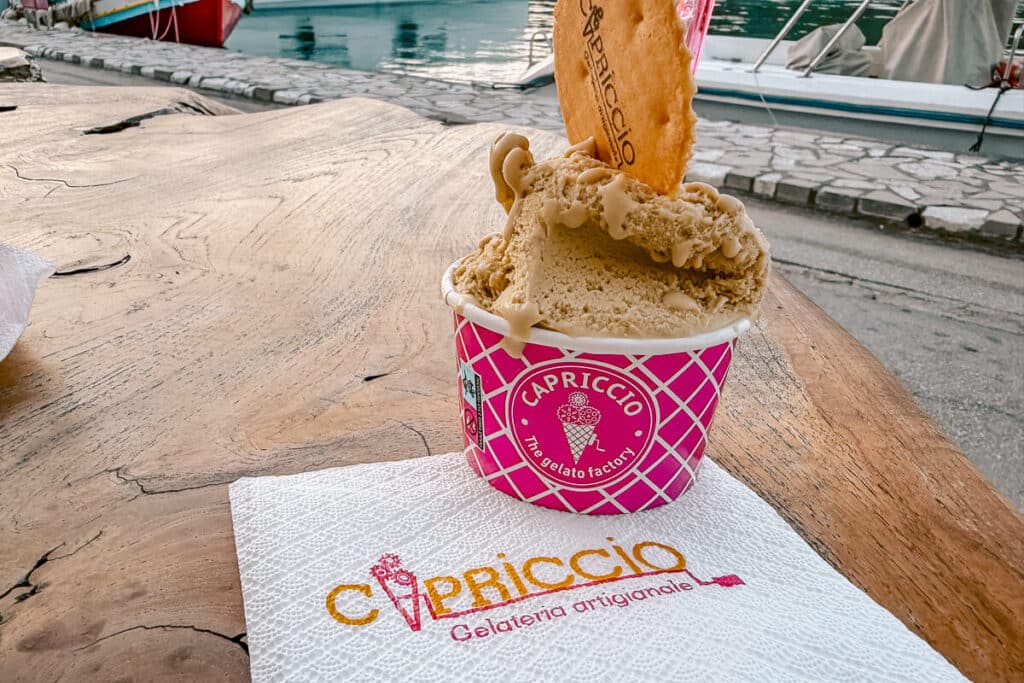 Cup of pistachio gelato from Capriccio in Paxos served on a wooden table near the harbor.