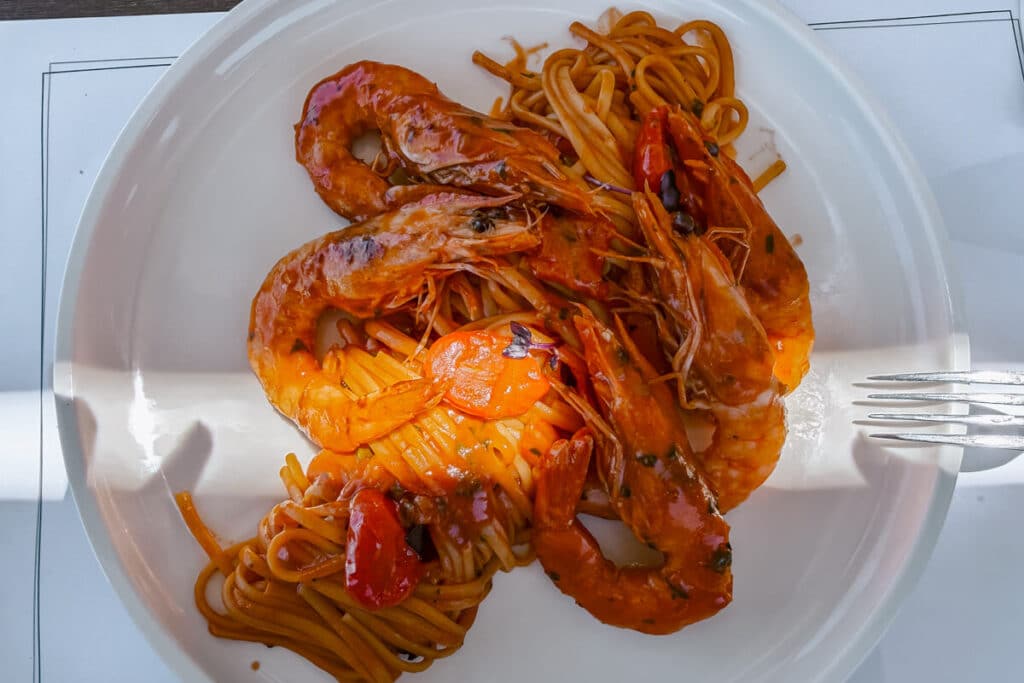 Plate of shrimp pasta in tomato sauce served at a beachside restaurant on Antipaxos Island.