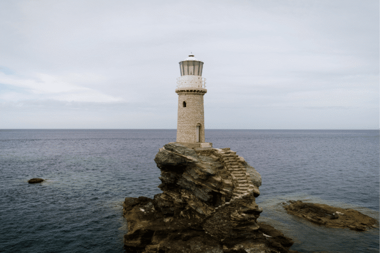 Tourlitis Lighthouse standing on a rocky islet in the sea near Chora, one of the best things to do in Andros, Greece.