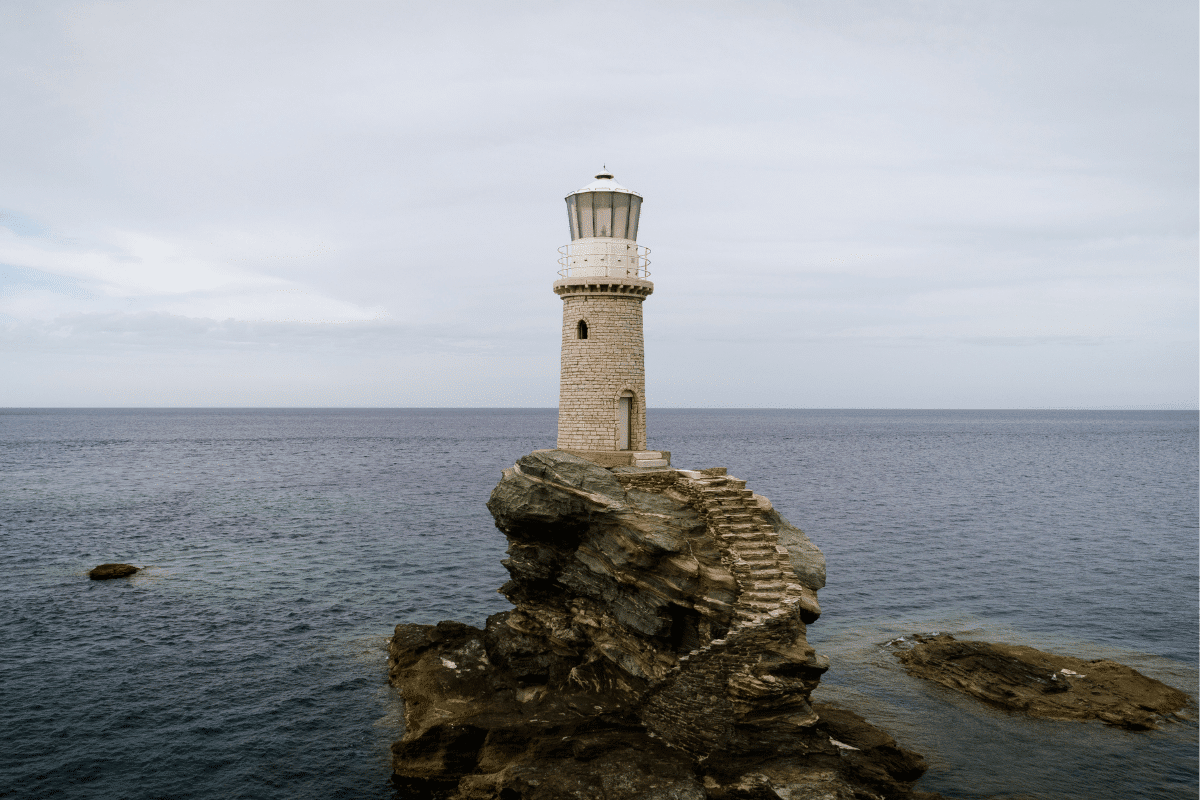 Tourlitis Lighthouse standing on a rocky islet in the sea near Chora, one of the best things to do in Andros, Greece.