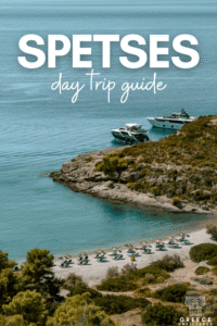 Turquoise bay with a pebble beach, sun loungers, and yachts in Spetses, with text reading “Spetses day trip guide.”